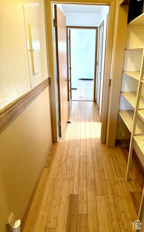 Corridor with light wood-style flooring and baseboards