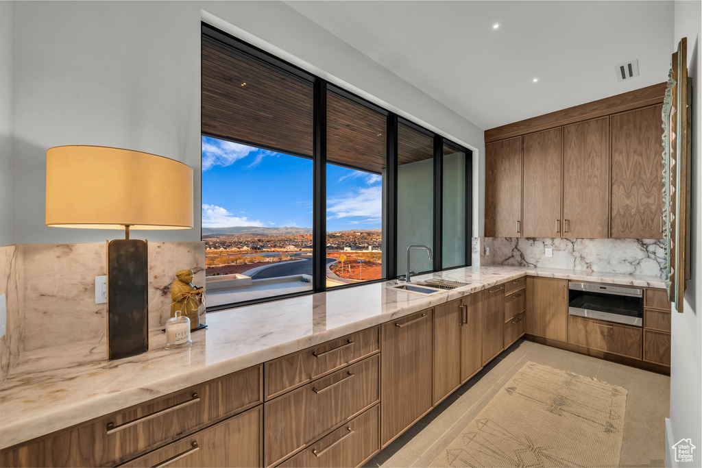 Kitchen with backsplash, light stone counters, and recessed lighting