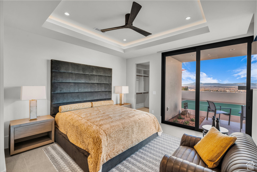 Bedroom with a raised ceiling, access to exterior, a spacious closet, recessed lighting, and a closet