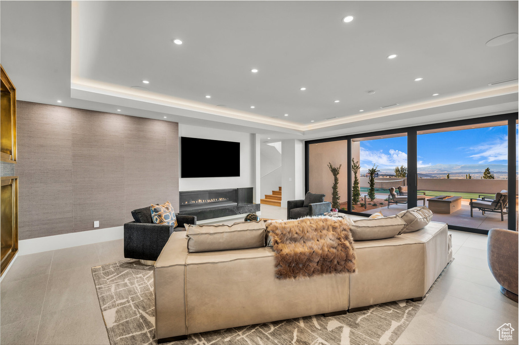 Living area featuring a raised ceiling, recessed lighting, a high end fireplace, and stairs