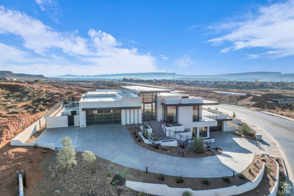 View of front of house with an attached garage, driveway, stucco siding, and a mountain view