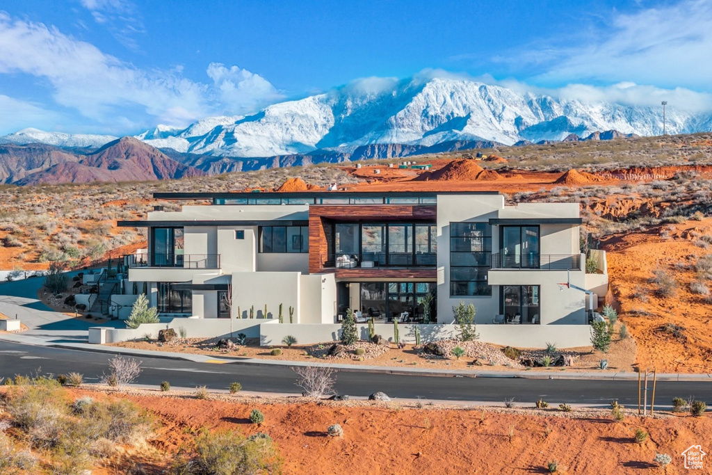 View of front of house featuring a mountain view, a balcony, and stucco siding