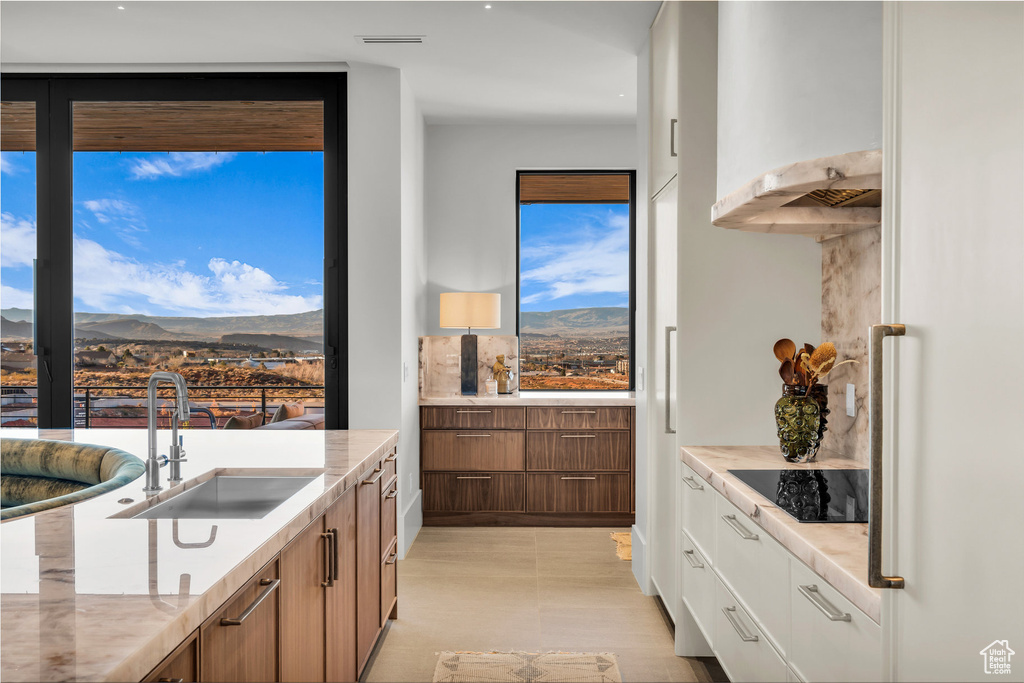 Kitchen featuring black electric cooktop, a mountain view, brown cabinets, and exhaust hood