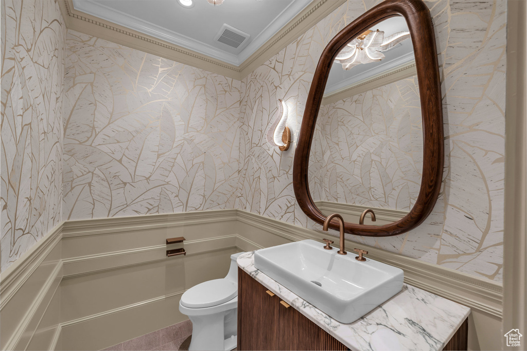 Bathroom featuring wallpapered walls, crown molding, a wainscoted wall, vanity, and a decorative wall