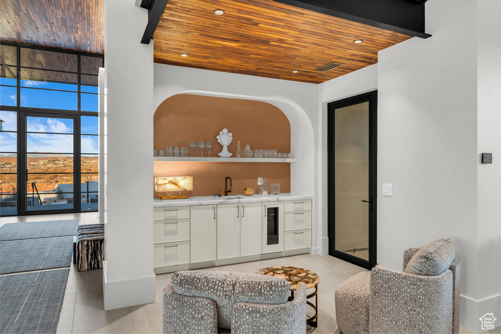 Indoor wet bar with wooden ceiling, light tile patterned floors, and wine cooler