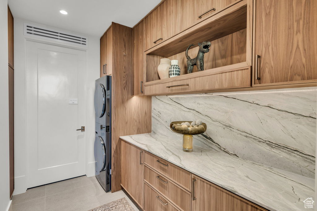 Laundry area with stacked washer / drying machine, light tile patterned floors, and recessed lighting