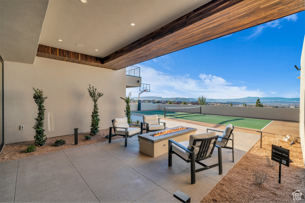 View of patio / terrace featuring a fire pit, a mountain view, and a tennis court