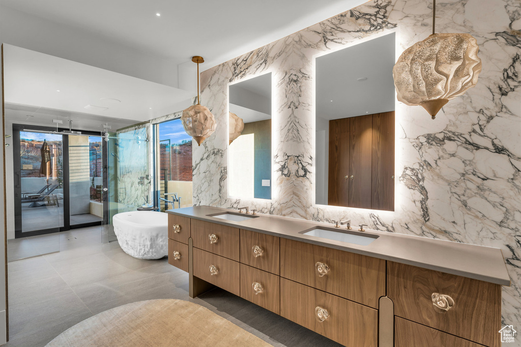 Full bathroom with double vanity, a freestanding tub, stone wall, tile walls, and an enclosed shower