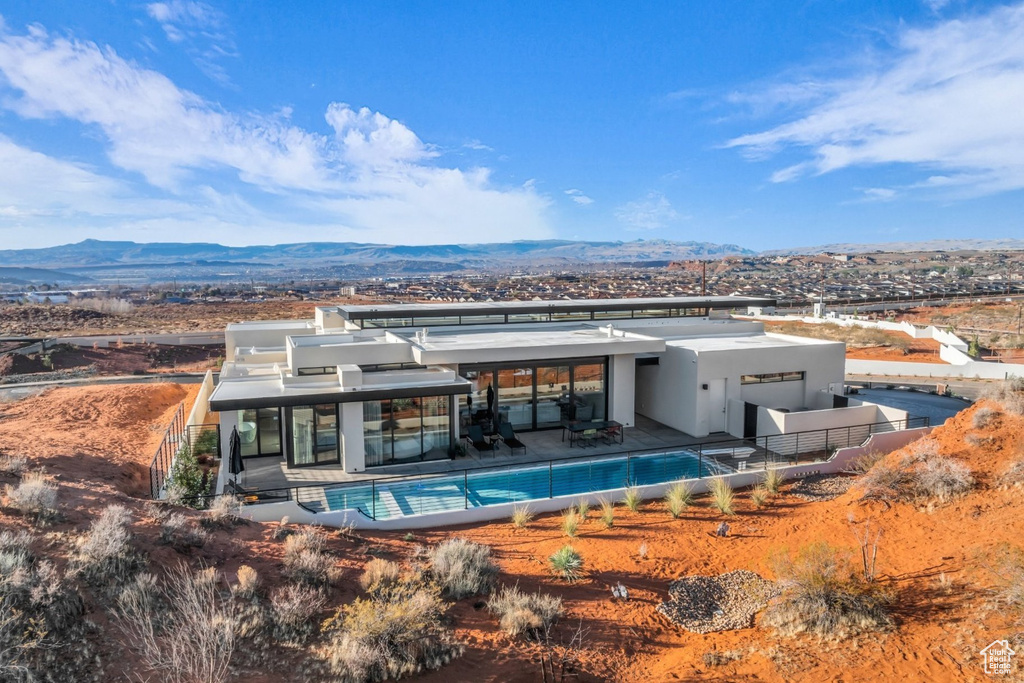 Rear view of house with a mountain view, an outdoor pool, and stucco siding