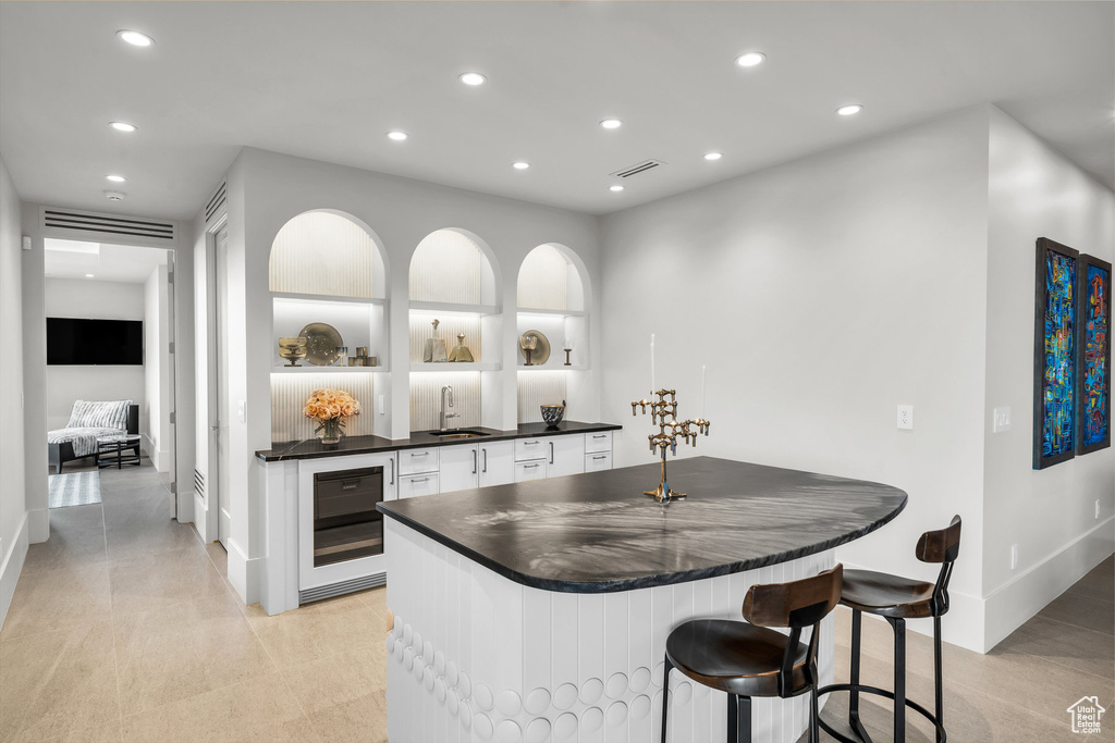 Indoor wet bar featuring wine cooler and recessed lighting
