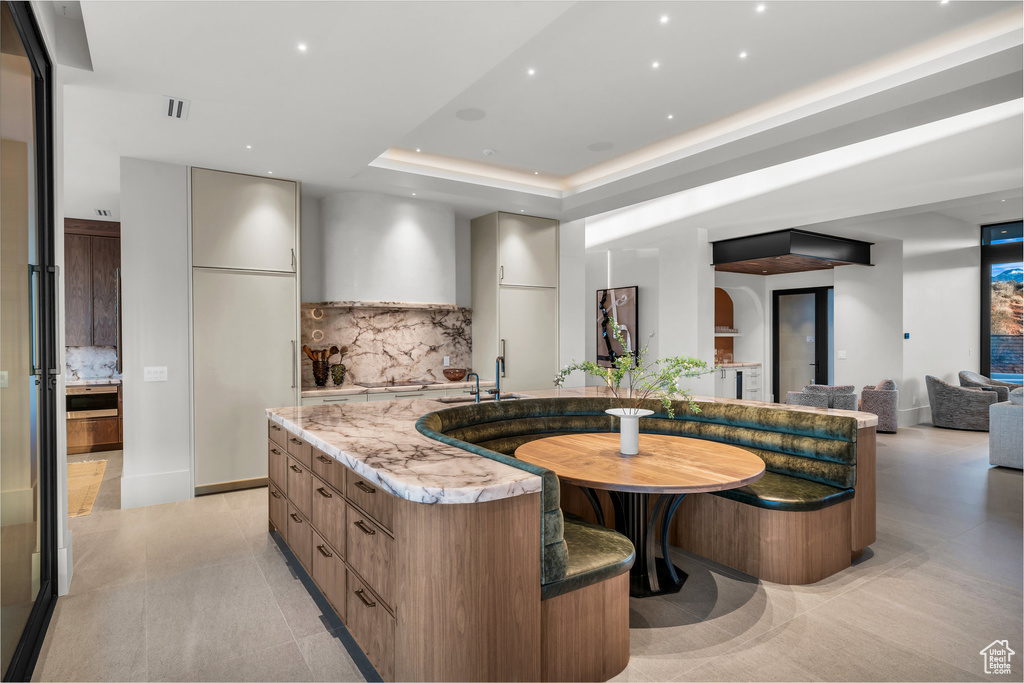 Kitchen featuring modern cabinets, backsplash, a spacious island, light stone countertops, and recessed lighting