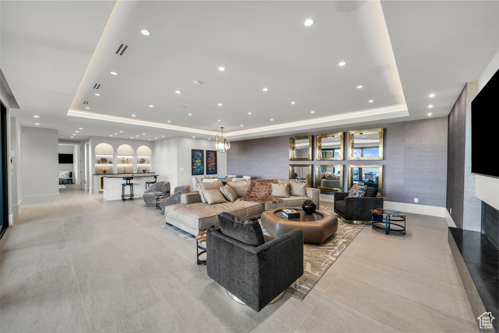 Living area with a raised ceiling, recessed lighting, a fireplace, and light tile patterned flooring