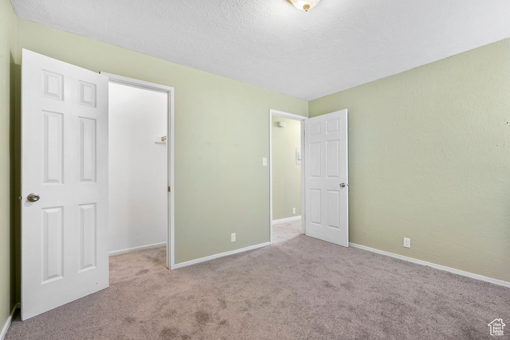 Unfurnished bedroom featuring light carpet and a textured ceiling