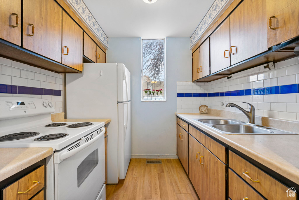 Kitchen featuring white electric stove, sink, backsplash, and light hardwood / wood-style flooring