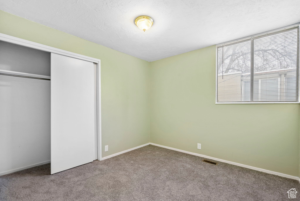 Unfurnished bedroom featuring light carpet, a closet, and a textured ceiling