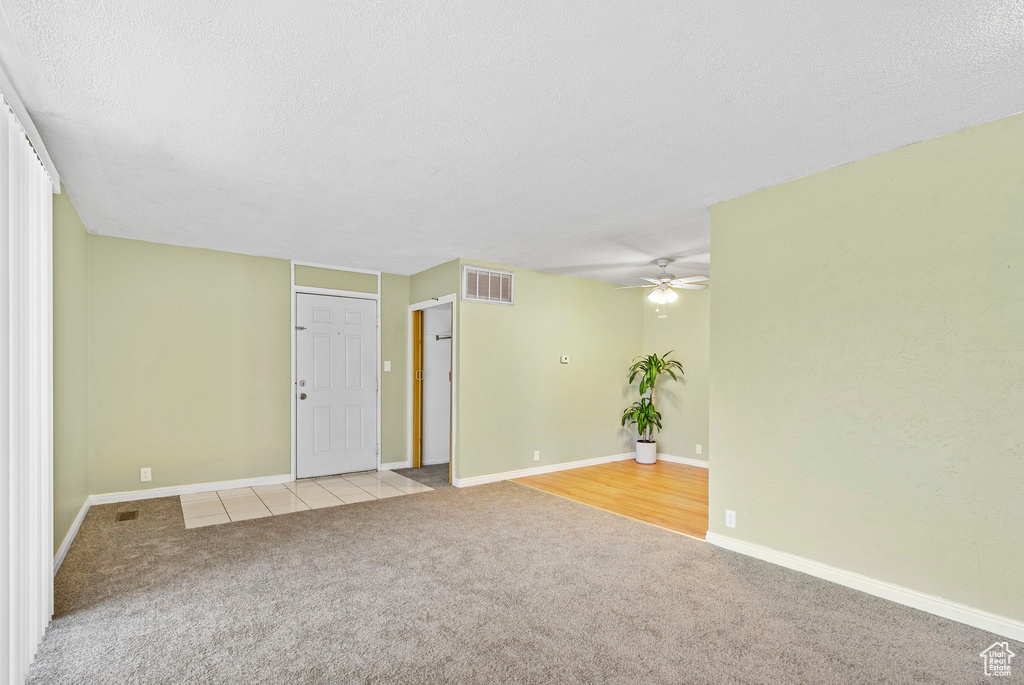 Carpeted spare room featuring ceiling fan and a textured ceiling