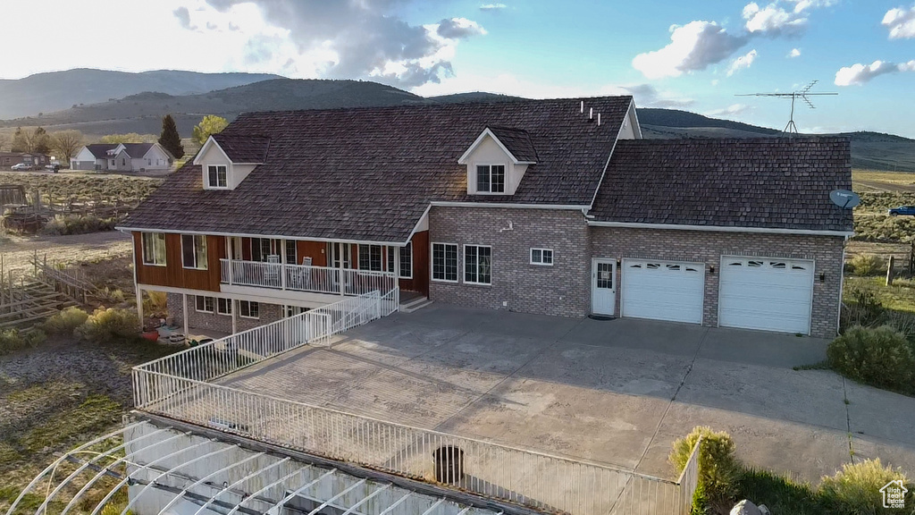View of front of home with brick siding, driveway, a garage, and a mountain view