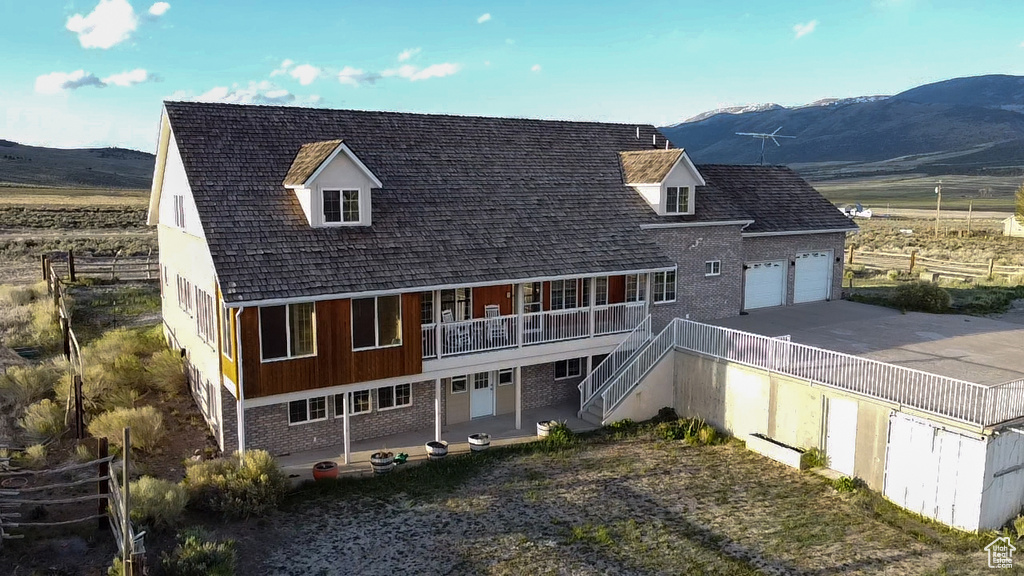 Rear view of property with a mountain view, brick siding, a garage, and stairway