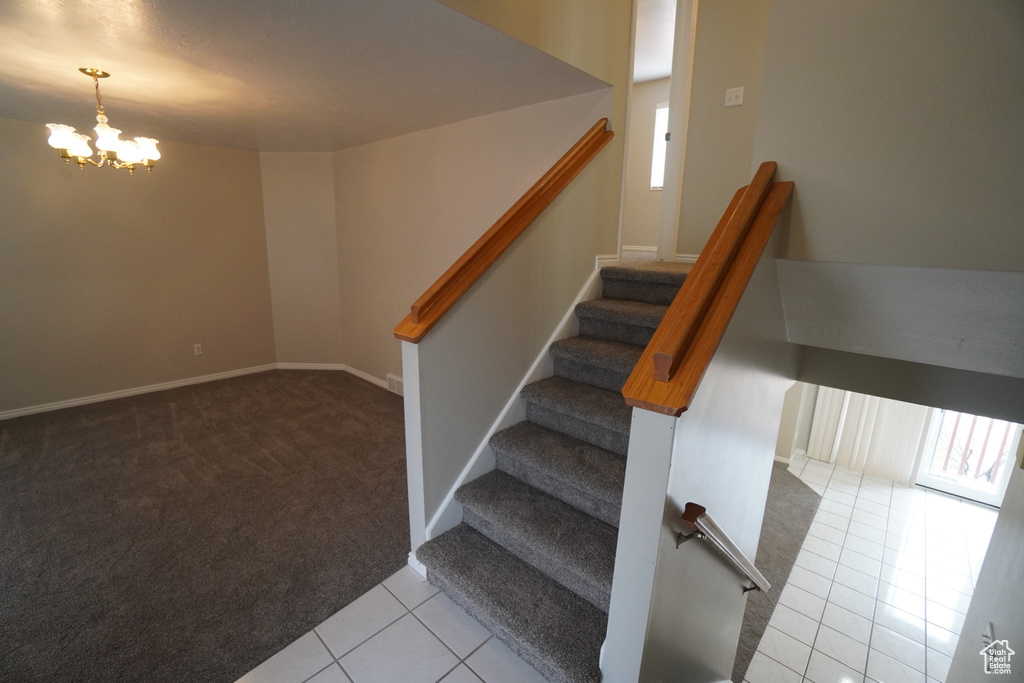 Staircase featuring tile patterned flooring and a chandelier