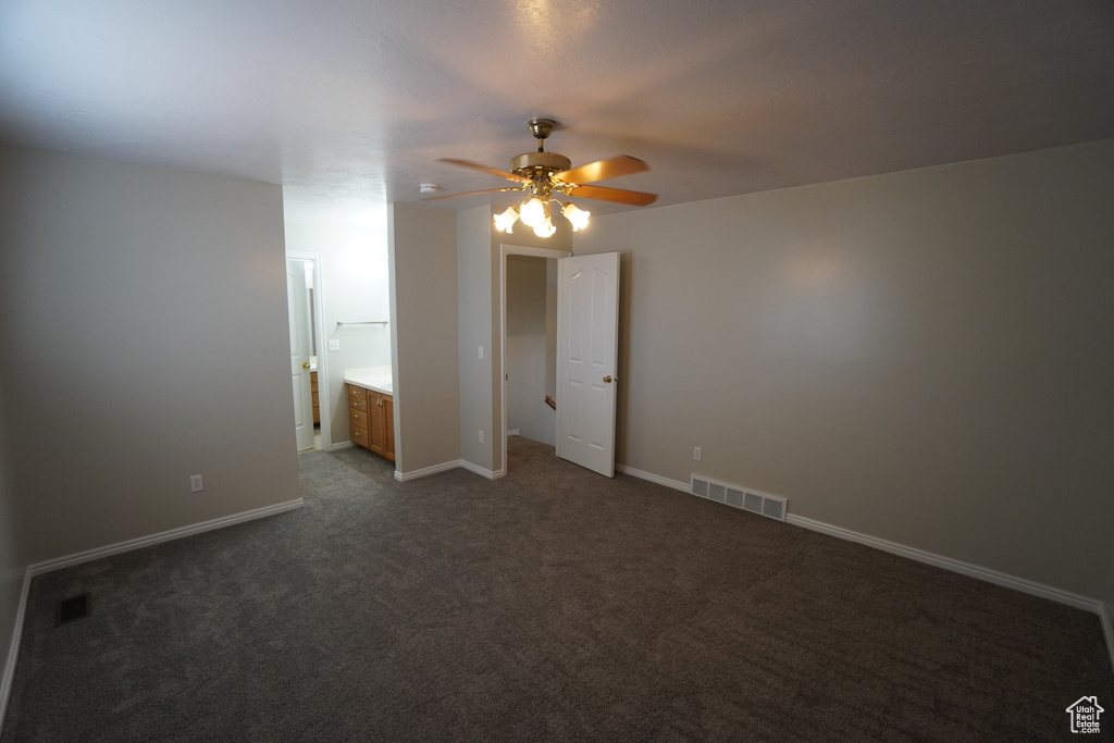 Unfurnished bedroom featuring connected bathroom, ceiling fan, and dark colored carpet