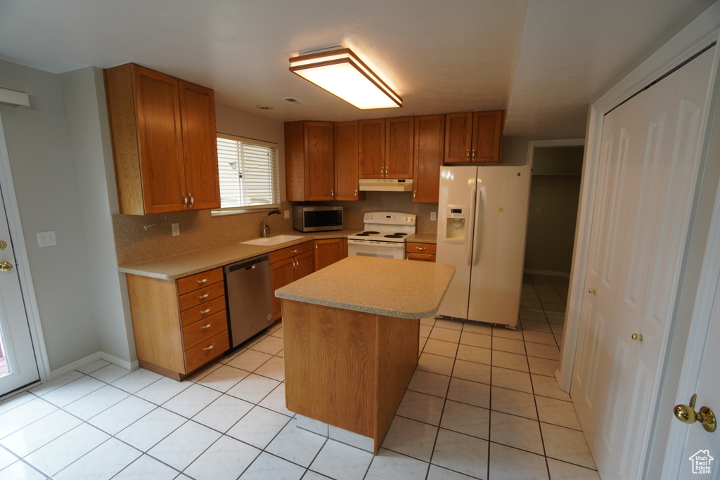 Kitchen with sink, tasteful backsplash, light tile patterned floors, appliances with stainless steel finishes, and a kitchen island