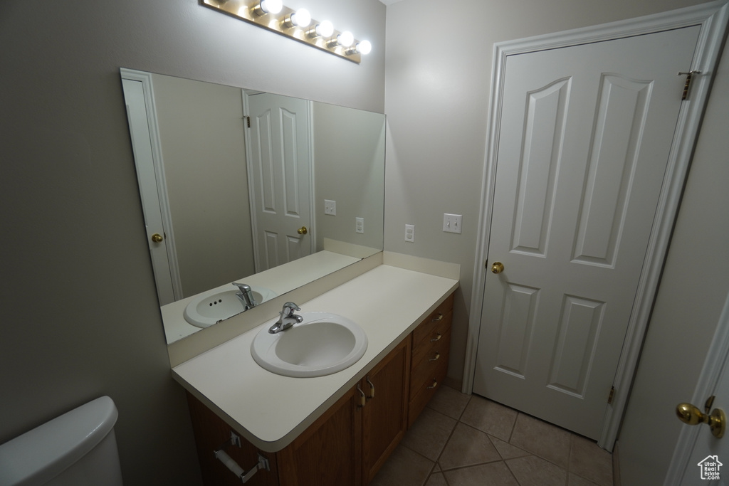 Bathroom featuring vanity, tile patterned flooring, and toilet