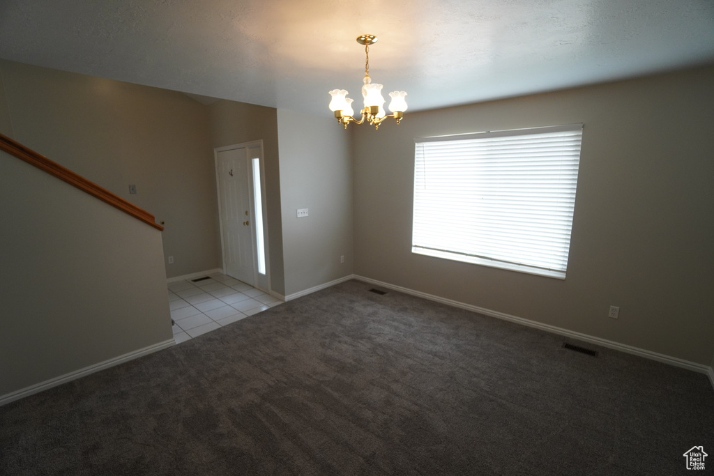 Carpeted empty room with a notable chandelier