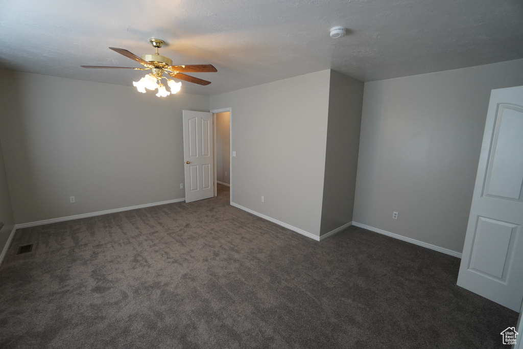 Spare room with ceiling fan and dark carpet