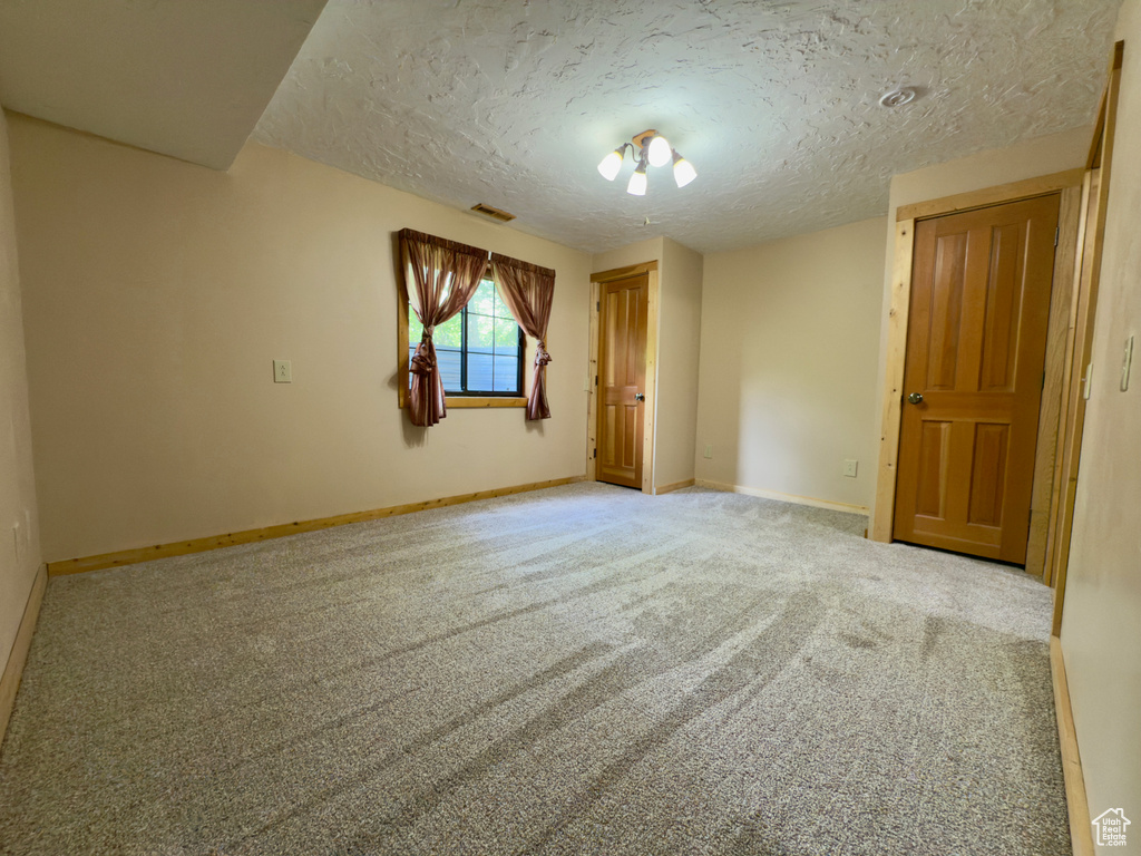 Carpeted empty room with a textured ceiling and baseboards