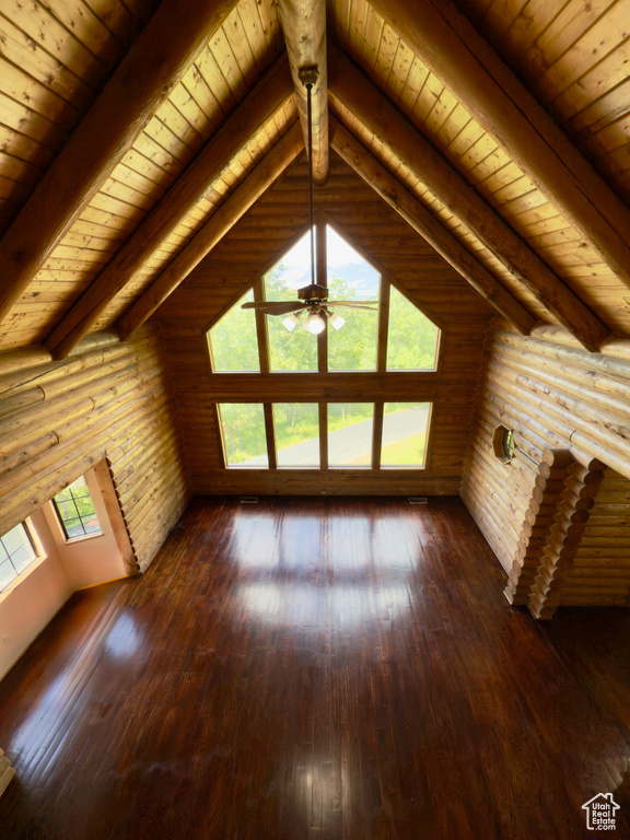 Unfurnished living room featuring dark wood finished floors, wood ceiling, a ceiling fan, and rustic walls