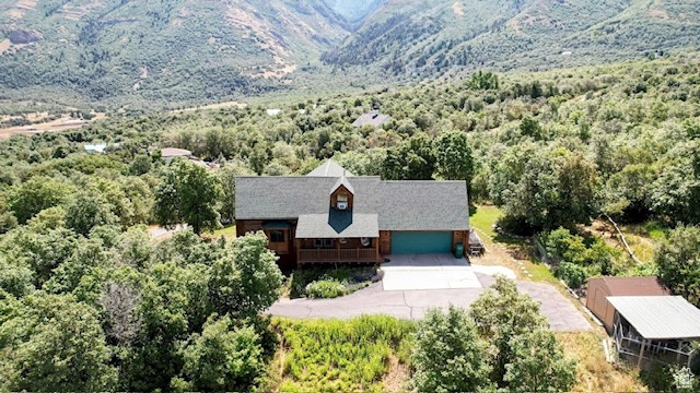 Aerial view of property and surrounding area featuring a forest and a mountain backdrop