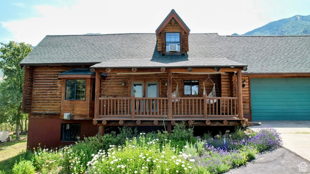 Log cabin with log siding, concrete driveway, a mountain view, and a garage