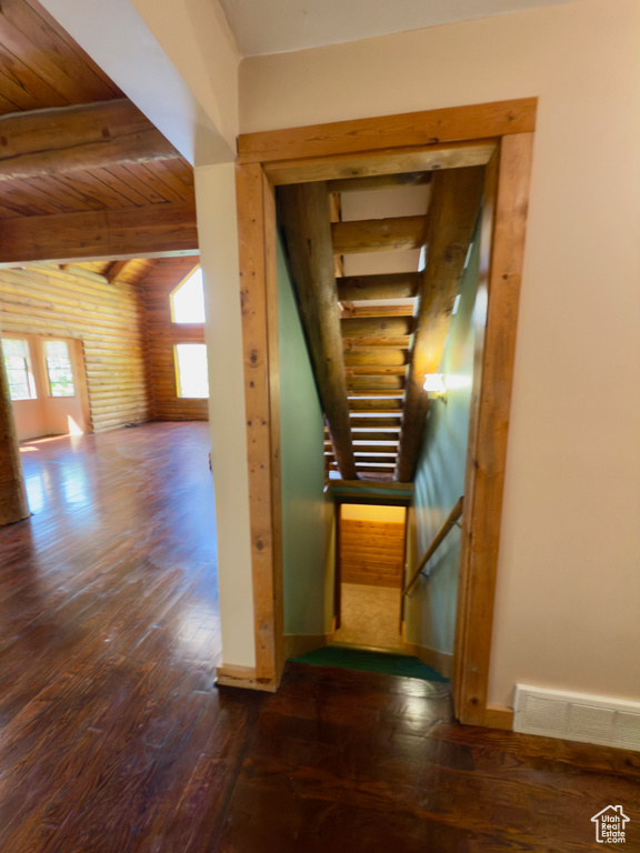 Staircase featuring wood finished floors, wood ceiling with exposed beams, and baseboards