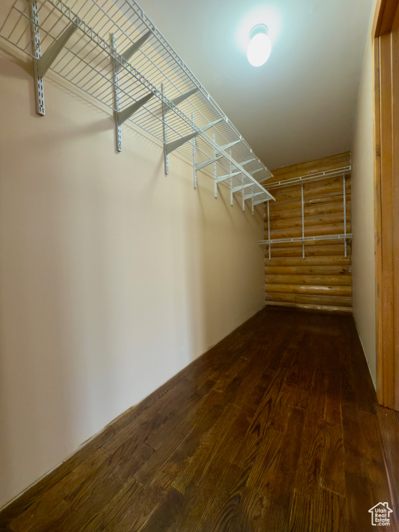 Walk in closet with dark wood-style floors