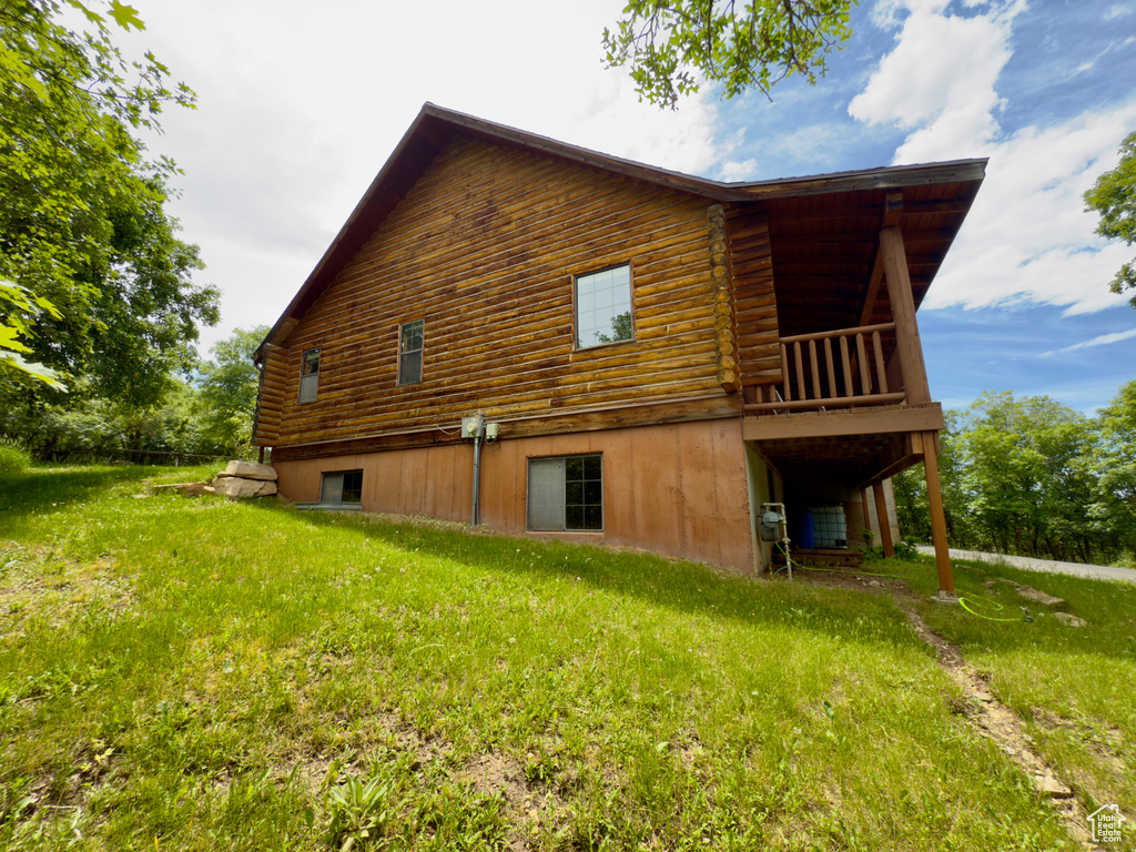 View of home\\\'s exterior featuring log siding, a wooden deck, and a yard