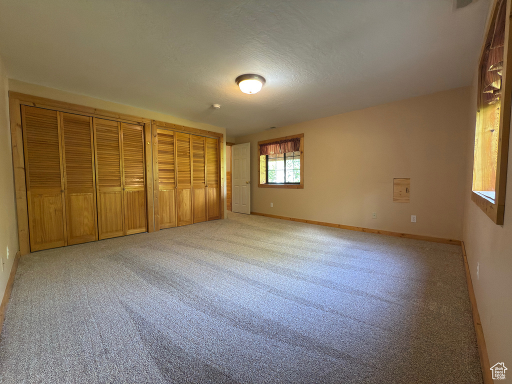 Unfurnished bedroom with multiple closets, light carpet, and baseboards