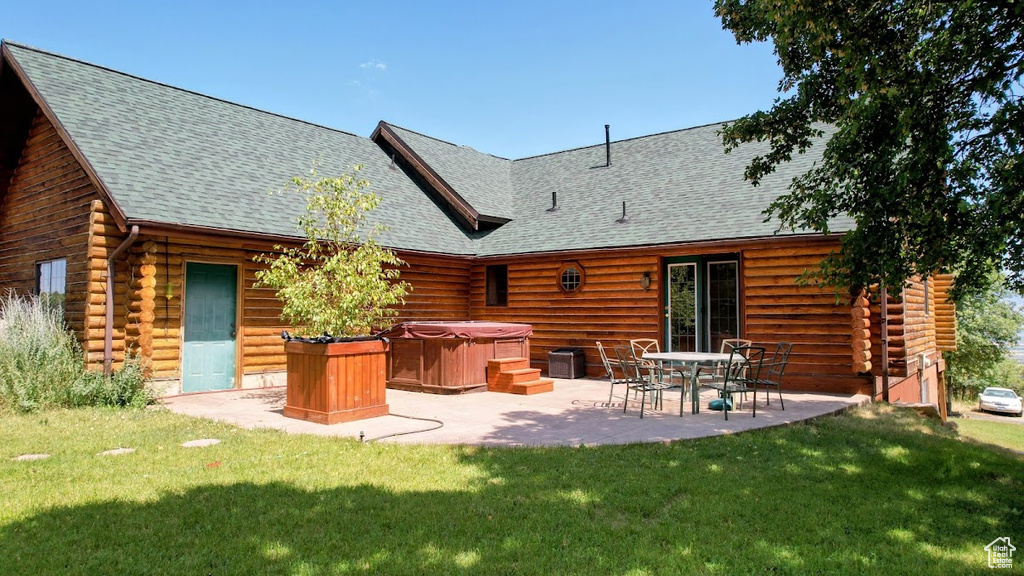 Rear view of house with a hot tub, log exterior, a patio, and a shingled roof
