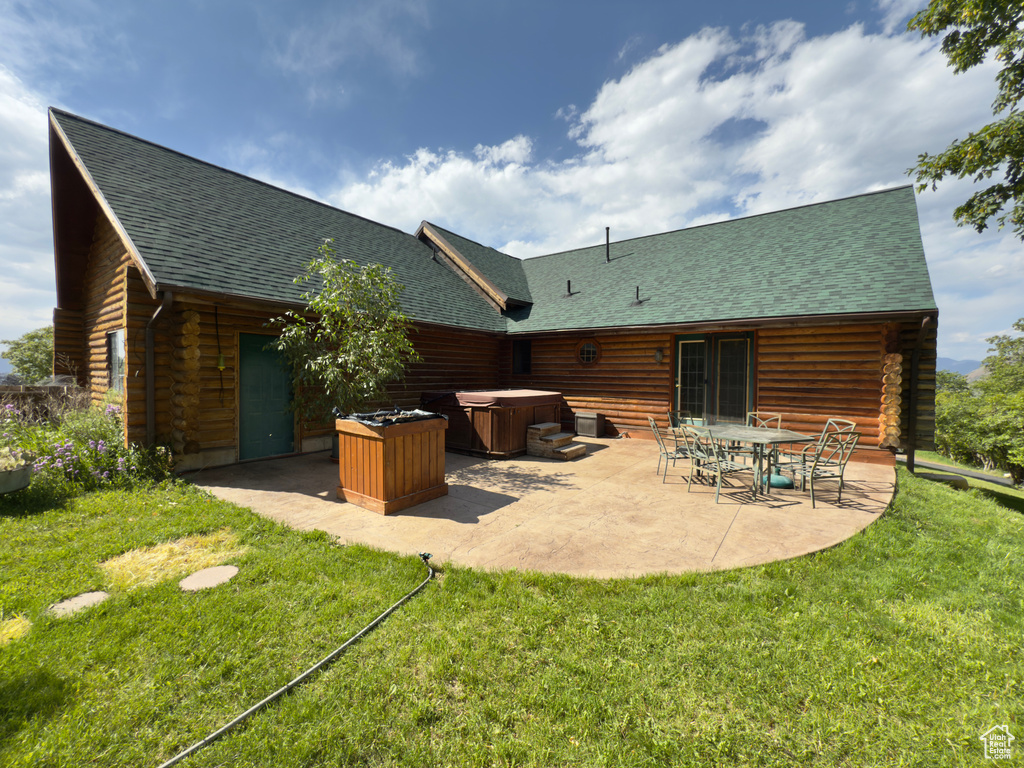 Back of house featuring a hot tub, a patio, roof with shingles, and log exterior