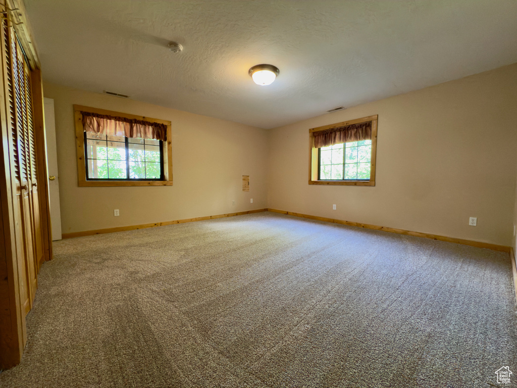 Unfurnished room featuring carpet, baseboards, a smoke detector, and a textured ceiling