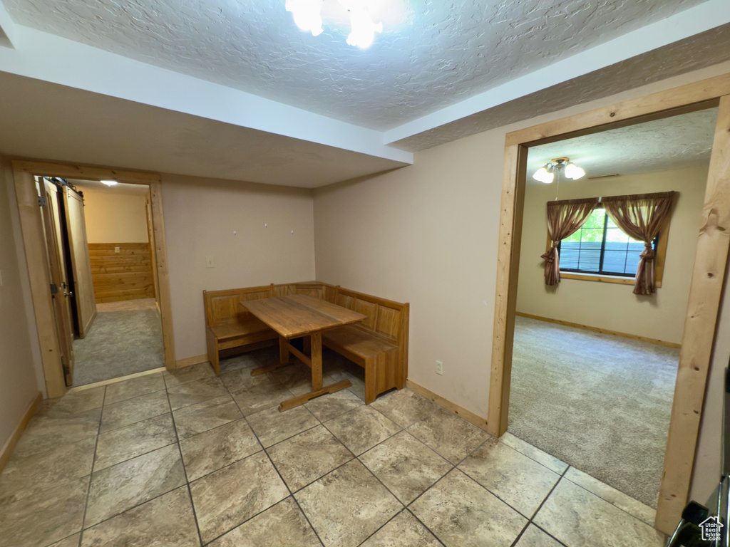Unfurnished dining area with a textured ceiling, baseboards, and light colored carpet
