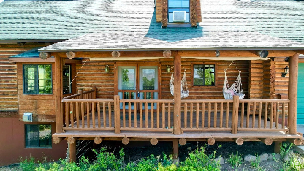 Back of house featuring a shingled roof, log siding, and a wooden deck