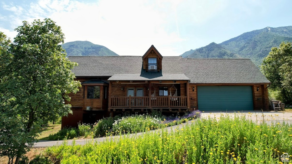 Cabin with a garage, a mountain view, driveway, and cooling unit