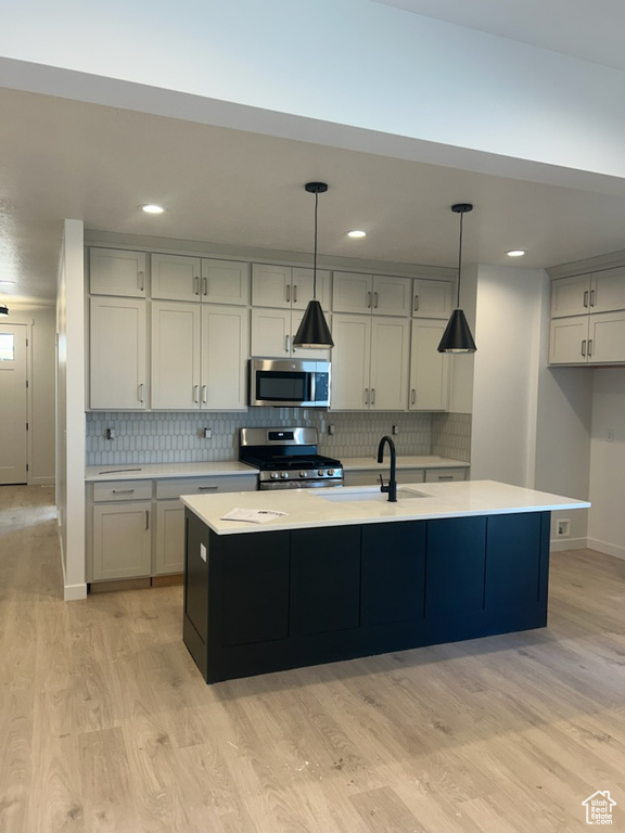 Kitchen with stainless steel appliances, a sink, light wood-style floors, light countertops, and recessed lighting