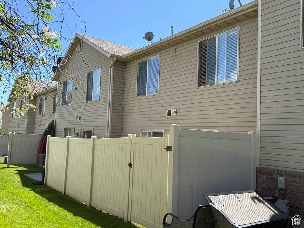 View of home's exterior with a yard, fence, and a gate