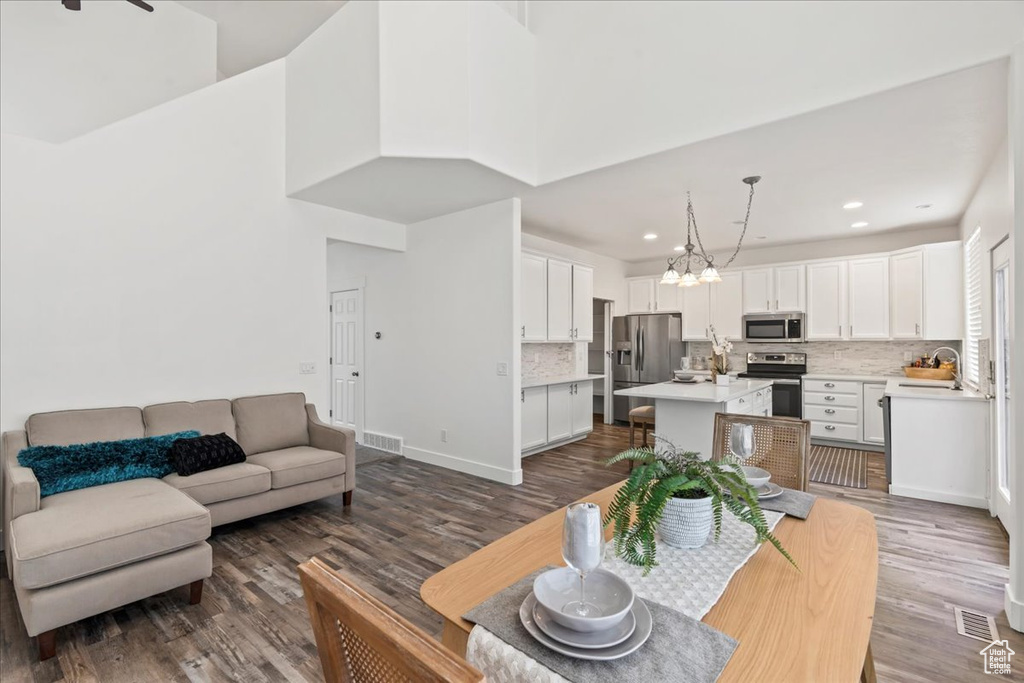 Living room with dark hardwood / wood-style floors, sink, a high ceiling, and a notable chandelier