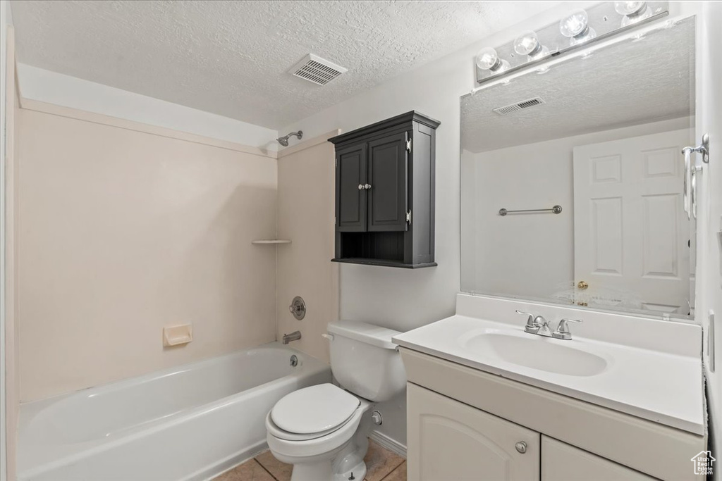 Full bathroom featuring tile patterned floors, toilet, tub / shower combination, a textured ceiling, and vanity