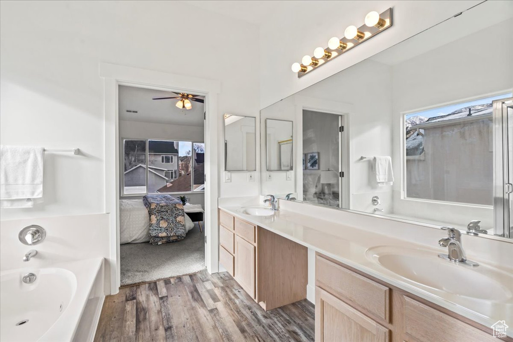 Bathroom featuring vanity, a bath, hardwood / wood-style flooring, and ceiling fan