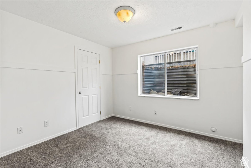 Carpeted empty room featuring a textured ceiling
