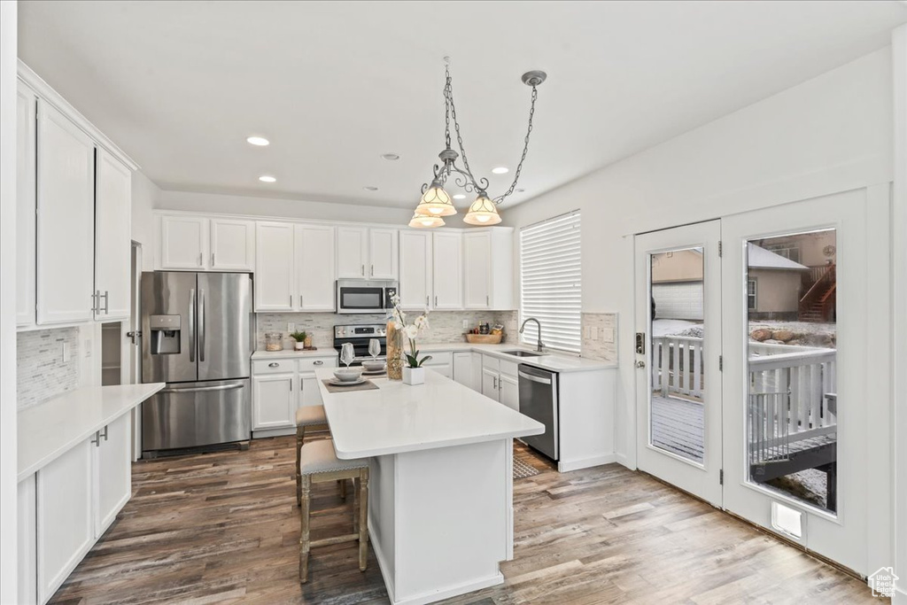 Kitchen featuring pendant lighting, a center island, white cabinets, and appliances with stainless steel finishes