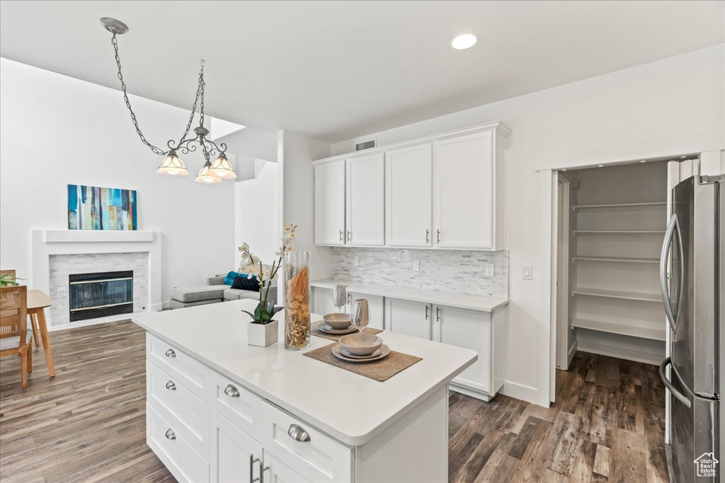 Kitchen featuring stainless steel refrigerator, decorative light fixtures, tasteful backsplash, white cabinets, and dark wood-type flooring